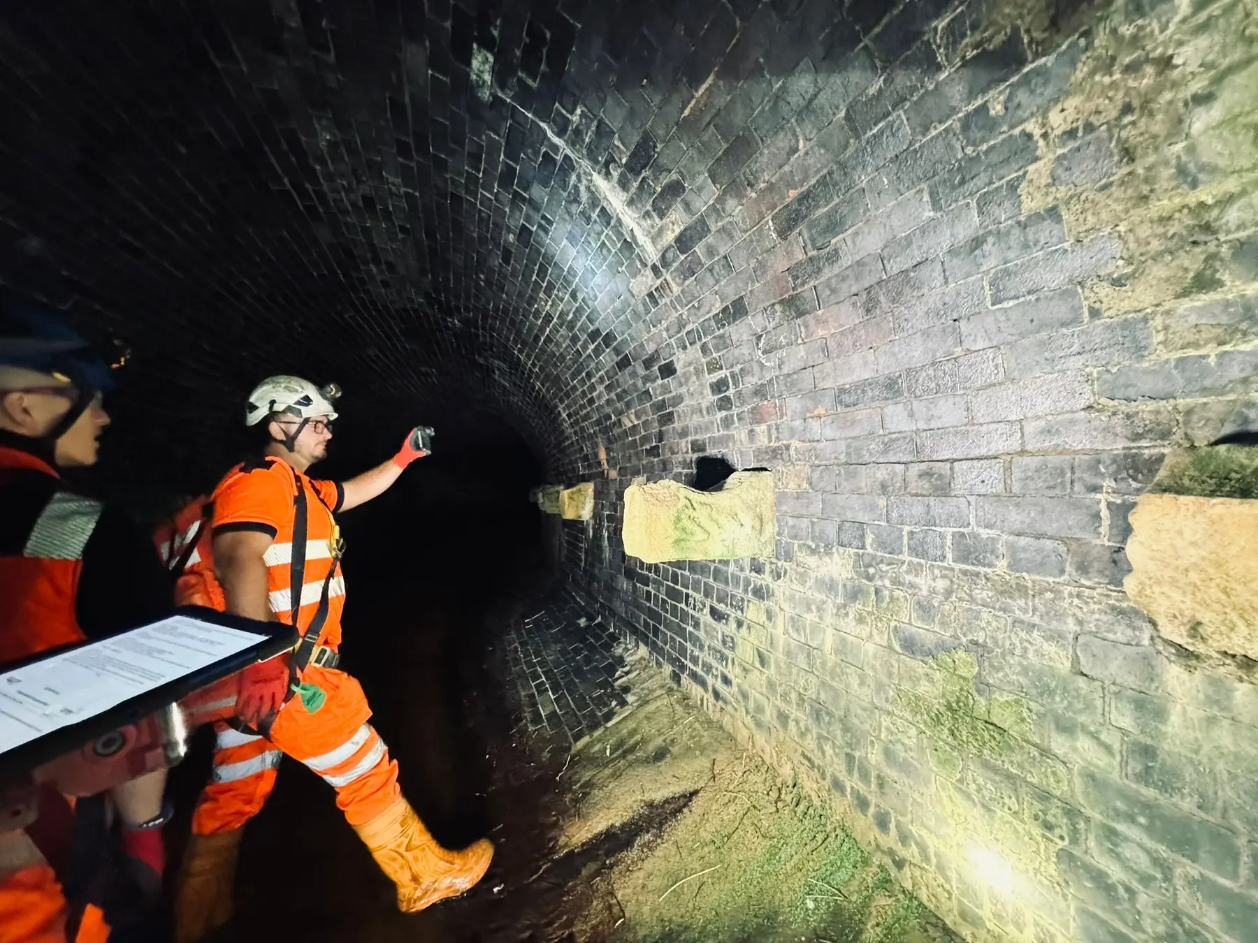 Operatives reviewing masonry condition inside a restricted infrastructure asset