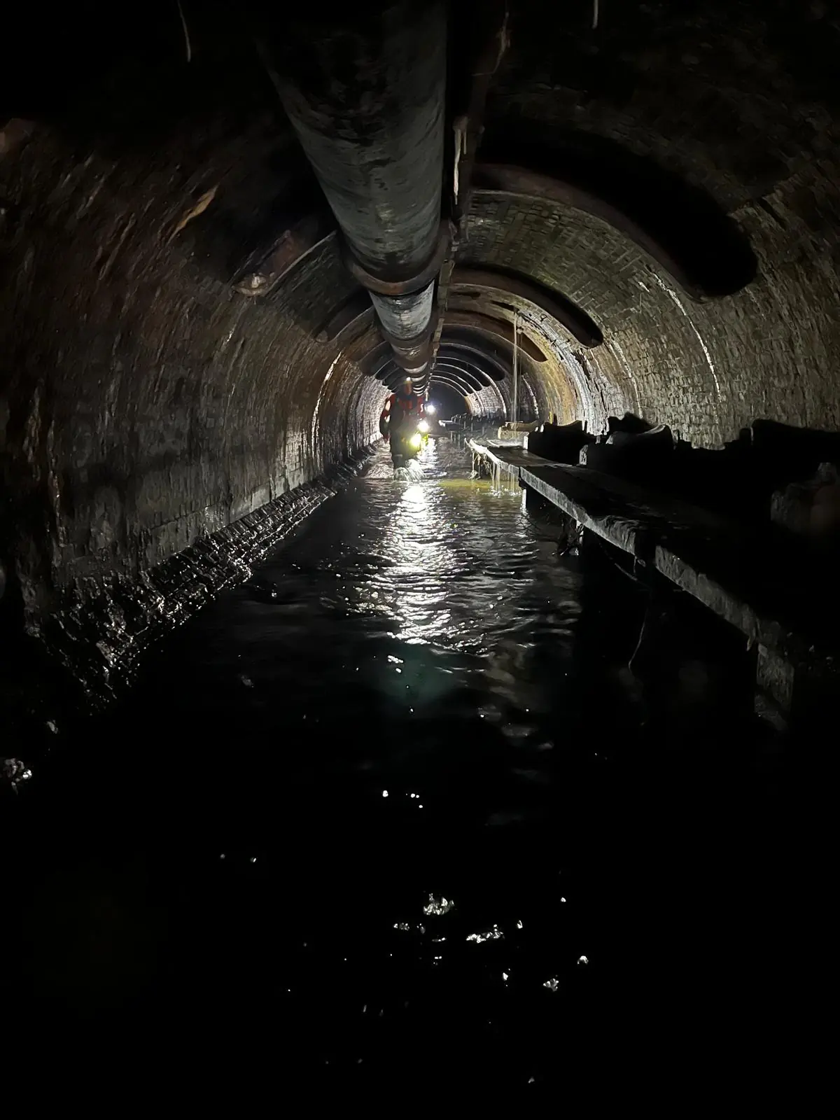 Restricted water-filled culvert with temporary service pipe and task lighting